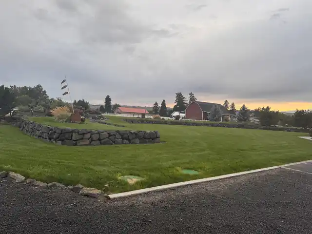 Wide commercial lawn at dusk with a stone wall