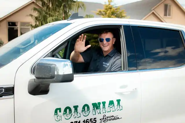 A Colonial team member waving from the window of a Colonial pickup truck