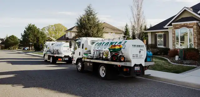 Two Colonial spray trucks on a residential street
